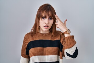 Poster - Young beautiful woman wearing striped sweater over isolated background shooting and killing oneself pointing hand and fingers to head like gun, suicide gesture.