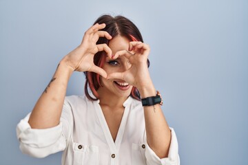 Canvas Print - Young caucasian woman wearing casual white shirt over isolated background doing heart shape with hand and fingers smiling looking through sign