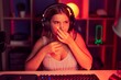 Young blonde woman playing video games wearing headphones smelling something stinky and disgusting, intolerable smell, holding breath with fingers on nose. bad smell