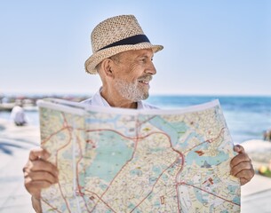 Canvas Print - Senior man smiling confident wearing summer hat holding map at seaside