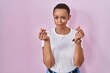 © Krakenimages.com - Beautiful african american woman standing over pink background doing money gesture with hands, asking for salary payment, millionaire business