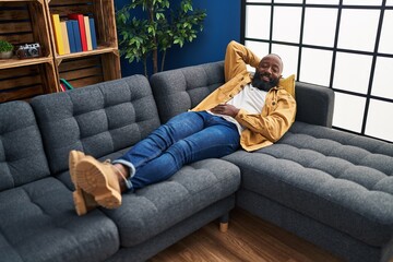 Sticker - Young african american man smiling confident relaxed lying on sofa at home