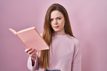 Sticker - Young caucasian woman reading a book over pink background skeptic and nervous, frowning upset because of problem. negative person.