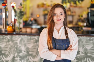 Wall Mural - Young caucasian woman waitress smiling confident standing with arms crossed gesture at restaurant