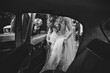 Happy bride and groom, newlywed wedding couple is sit in a retro car on a country road for honeymoon after the ceremony. The best day and marriage. Just married. Black and white photo.