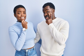 Sticker - Young african american couple standing over blue background thinking worried about a question, concerned and nervous with hand on chin