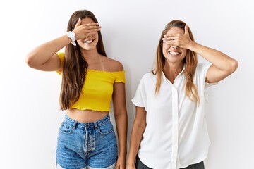 Wall Mural - Mother and daughter together standing together over isolated background smiling and laughing with hand on face covering eyes for surprise. blind concept.