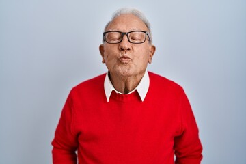 Canvas Print - Senior man with grey hair standing over isolated background looking at the camera blowing a kiss on air being lovely and sexy. love expression.