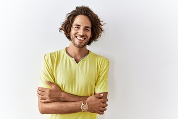 Wall Mural - Young hispanic man standing over isolated background happy face smiling with crossed arms looking at the camera. positive person.