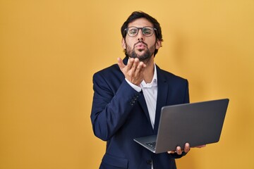 Canvas Print - Handsome latin man working using computer laptop looking at the camera blowing a kiss with hand on air being lovely and sexy. love expression.