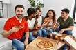 © Krakenimages.com - Group of young friends smiling happy eating italian pizza sitting on the sofa at home.