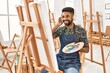 © Krakenimages.com - Young african american artist man smiling happy listening to music and painting at art studio.