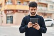 © Krakenimages.com - Young arab man with relaxed expression using touchpad at street