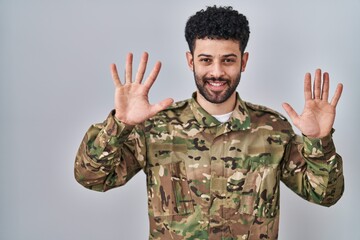 Poster - Arab man wearing camouflage army uniform showing and pointing up with fingers number ten while smiling confident and happy.