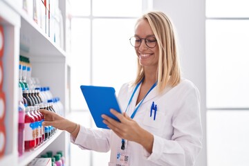 Canvas Print - Young blonde woman pharmacist using touchpad working at pharmacy