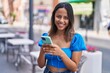© Krakenimages.com - Young hispanic woman smiling confident using smartphone at street