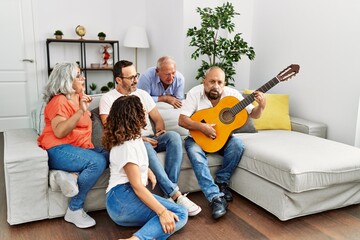 Poster - Group of middle age friends having party playing classical guitar sitting on the sofa at home.