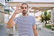 © Krakenimages.com - Young hispanic man with beard outdoors at the city smiling positive doing ok sign with hand and fingers. successful expression.