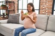 © Krakenimages.com - Young latin woman pregnant eating salad sitting on sofa at home