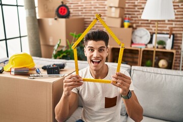 Wall Mural - Young hispanic man moving to a new home celebrating crazy and amazed for success with open eyes screaming excited.