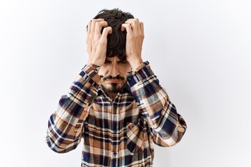 Poster - Hispanic man with beard standing over isolated background suffering from headache desperate and stressed because pain and migraine. hands on head.