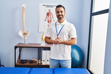 Canvas Print - Young hispanic man physiotherapist smiling confident standing at rehab clinic