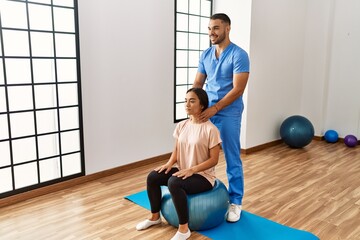 Sticker - Latin man and woman wearing physiotherapist uniform using fit ball massaging neck at rehab center