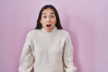 Wall Mural - Young south asian woman standing over pink background afraid and shocked with surprise and amazed expression, fear and excited face.