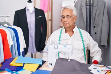 Sticker - Middle age man with grey hair dressmaker using sewing machine skeptic and nervous, frowning upset because of problem. negative person.