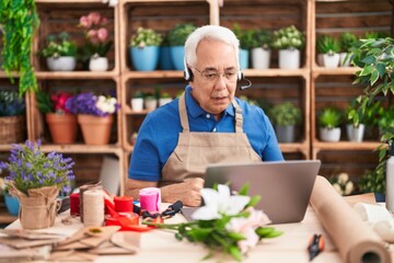 Poster - Middle age man with grey hair working at florist shop doing video call scared and amazed with open mouth for surprise, disbelief face