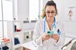 © Krakenimages.com - Young beautiful hispanic woman doctor smiling confident using smartphone at clinic
