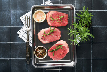 Steaks. Fresh Filet mignon Steaks with spices rosemary and pepper in kitchen tray on light gray background. Top view.