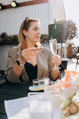 Wall Mural - Beautiful Woman eating fresh oysters and drinking chilled prosecco wine on the summer sunset in restaurant. Seafood delicacies