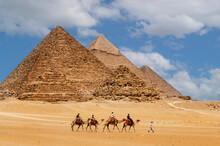 Cairo, Egypt. 08.25.2022. Group Of Tourists Riding Camels Seeing The Pyramids Of Menkaure, Chephren And Cheops.