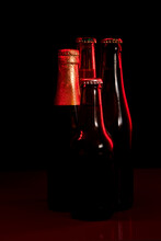 Silhouettes Of Four Beer Bottles On A Black Background And Lit With Red Light