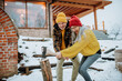 © Halfpoint - Senior couple chopping wood together in front of their house, during cold winter day.