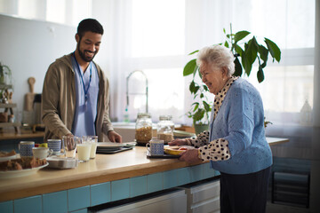 Wall Mural - Young caregiver serving breakfast to elderly woman in nursing home care center.