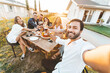 © Davide Angelini - Group of happy friends taking selfie at bbq outdoor dinner in home garden - Multiracial young people eating food and having fun at barbecue backyard house party - Youth and friendship concept