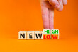 New low or high symbol. Concept words New high and New low on wooden cubes. Businessman hand. Beautiful orange table orange background. Business new low or high concept. Copy space.