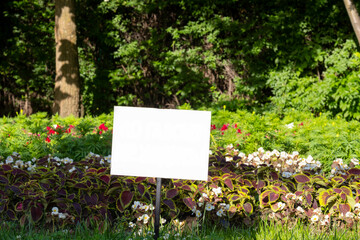 Sign on a flowerbed in the park with free space for text.