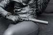 A girl in leather clothes sits on a sofa with a pistol with a silencer in her hand, close-up photo.