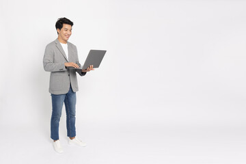 Happy young Asian business man using laptop computer and standing isolated on white background, Full body composition