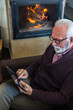 © Solid photos - Senior man on the video call sitting in front of the fireplace in winter