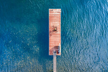 Wooden Dock On A Lake Overhead Aerial With Clear Blue Water.