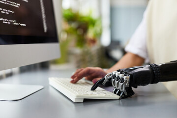 Close-up of woman with disability typing on keyboard while working with computer program at her workplace