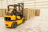 Fototapeta Sawanna - Hispanic operator driving a forklift stacking bags in an industrial plant in Latin America