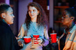 © Seventyfour - Group of young intercultural women with drinks in red cups having chat while enjoying gathering or home party on weekend night