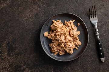 Poster - Canned tuna fish on the plate on black table.