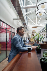 Handsome businessman standing in office during break and use phone