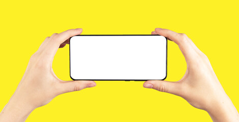 Aufkleber - Hands holding phone mockup in horizontal position for watching video on yellow background. Smartphone template with empty display.